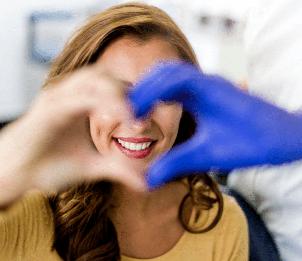 Smiling dental patient making heart shape with hands