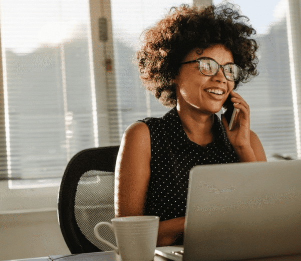 Therapist on phone at desk smiling using a hipaa-compliant phone system